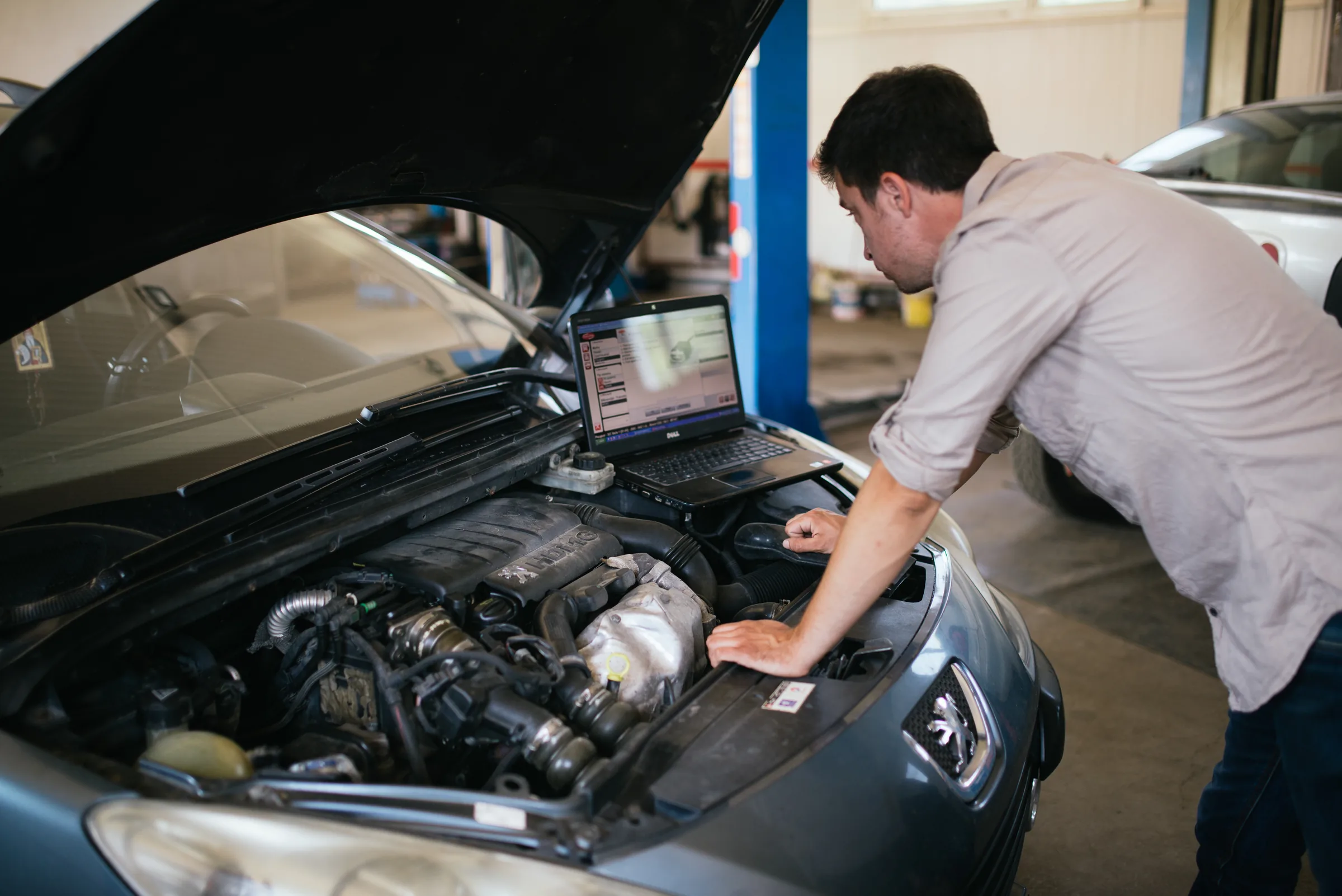 Mechanik s počítačem u automobilu při ilustrativní diagnostice